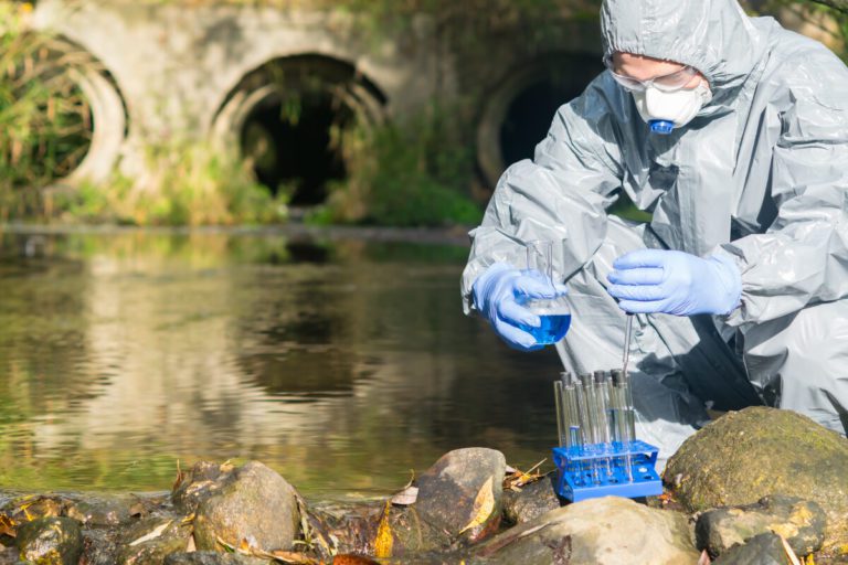 person in a hazmat suit testing water for contamination