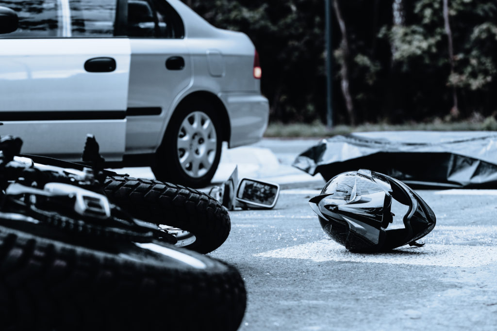 motorcycle accident scene with car and motorcycle parts on the ground 