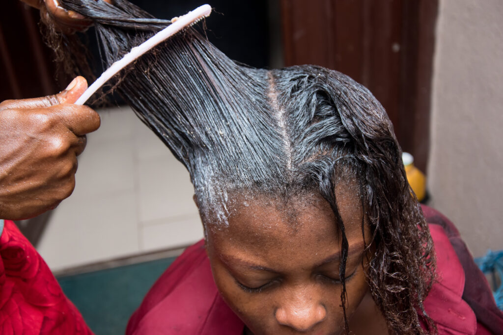 black woman having her hair combed with product