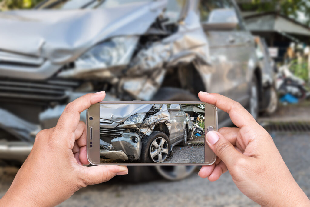 hands holding phone taking picture of car accident