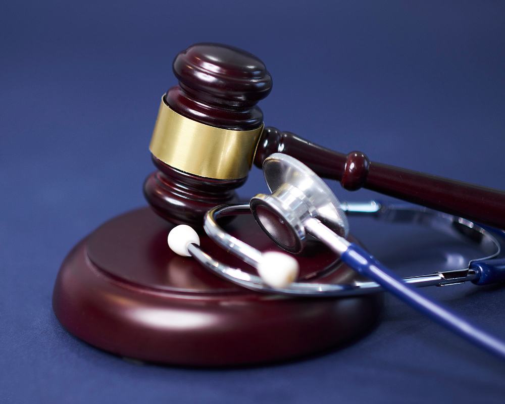 gavel and stethoscope on a blue table top