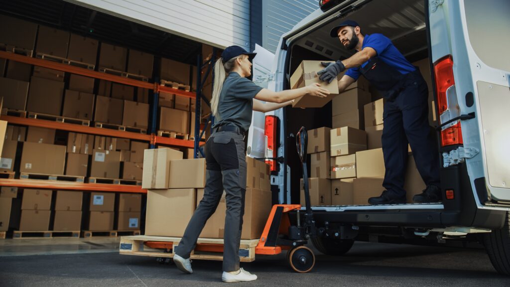 woman and a man loading packages into a van outside a warehouse