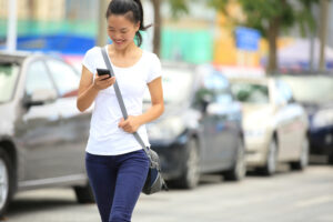 A woman walking while on the phone in a parking lot. What common factors lead to collisions in parking lots.