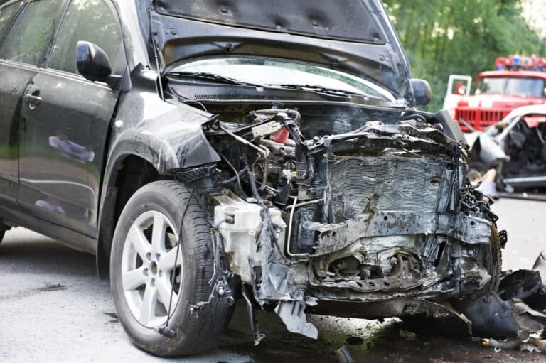 A smashed front end of a car after a car accident. What should I do at the scene of a car accident?