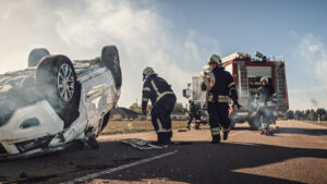 First responders assisting the driver of a tipped car after a truck accident.