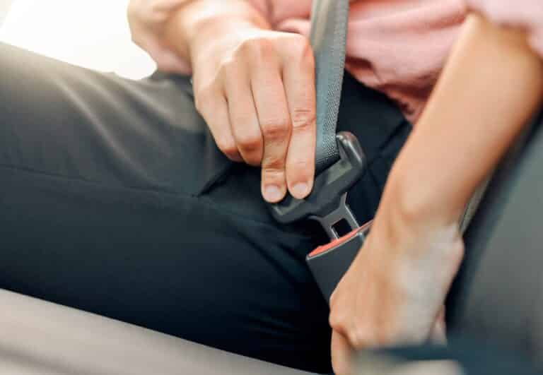 A Lyft passenger buckling their seatbelt, wondering if they can sue Lyft for an accident.