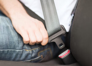 An Uber passenger buckling their seatbelt, wondering if they can sue Uber for an accident.