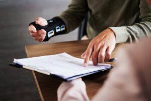 A man with a wrist brace reviewing a personal injury settlement. Are personal injury settlements taxable in Rhode Island?