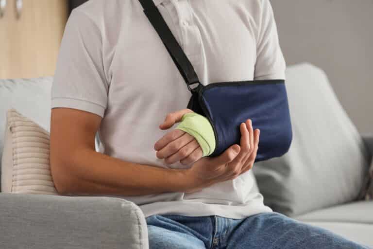 A man with his arm in a sling, wondering, “Can a lawsuit be reopened after settlement in Rhode Island?