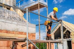 Construction worker wearing a fall protection harness while framing a roof